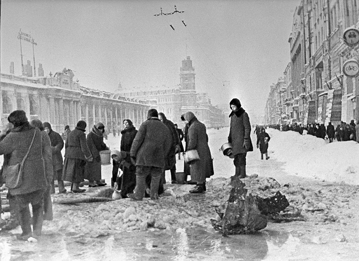 Жители блокадного города набирают воду из пробитого при обстреле водопровода. Фото: Борис Кудояров / РИА Новости