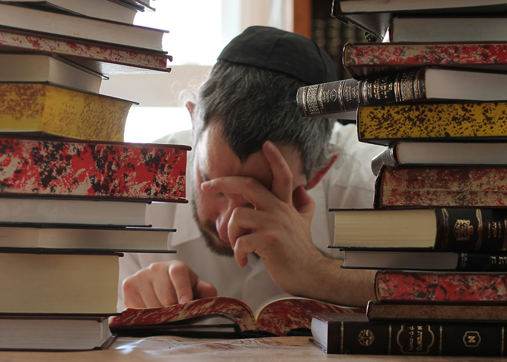 Мужчина изучает книги по иудаизму. Фото: menachem weinreb / Unsplash