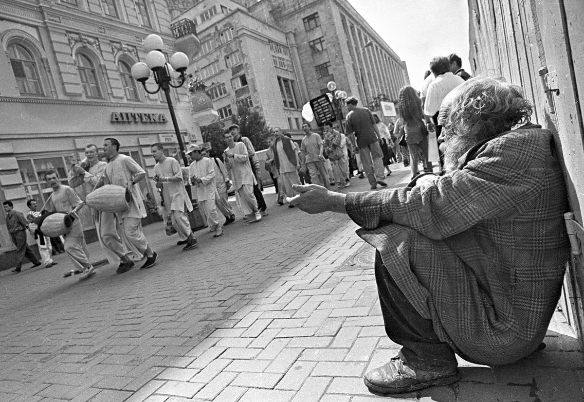 Нищий просит милостыню на улице Старый Арбат, мимо проходят прихожане Московского храма Кришны, 1995 год. Фото: Илья Питалев /&nbsp;РИА Новости