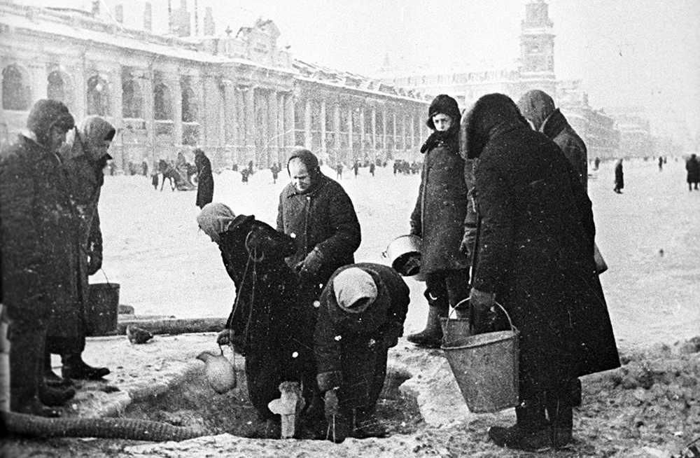 Жители блокадного Ленинграда набирают воду, появившуюся после артобстрела в пробоинах в асфальте на Невском проспекте, декабрь 1941 года. Фото: Борис Кудояров / РИА Новости