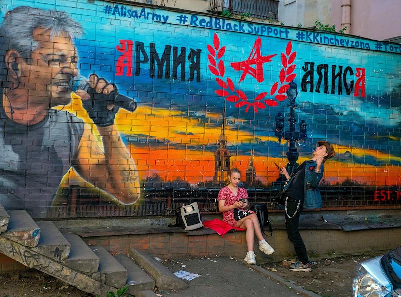 Молодые люди на фоне граффити с изображением солиста группы "Алиса" Константина Кинчева на площади Восстания. Фото:&nbsp;Майя Жинкина / Коммерсантъ